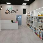Vista del interior de Pets & Us con el mostrador de atención al cliente y estanterías llenas de productos para el cuidado y bienestar de las mascotas.